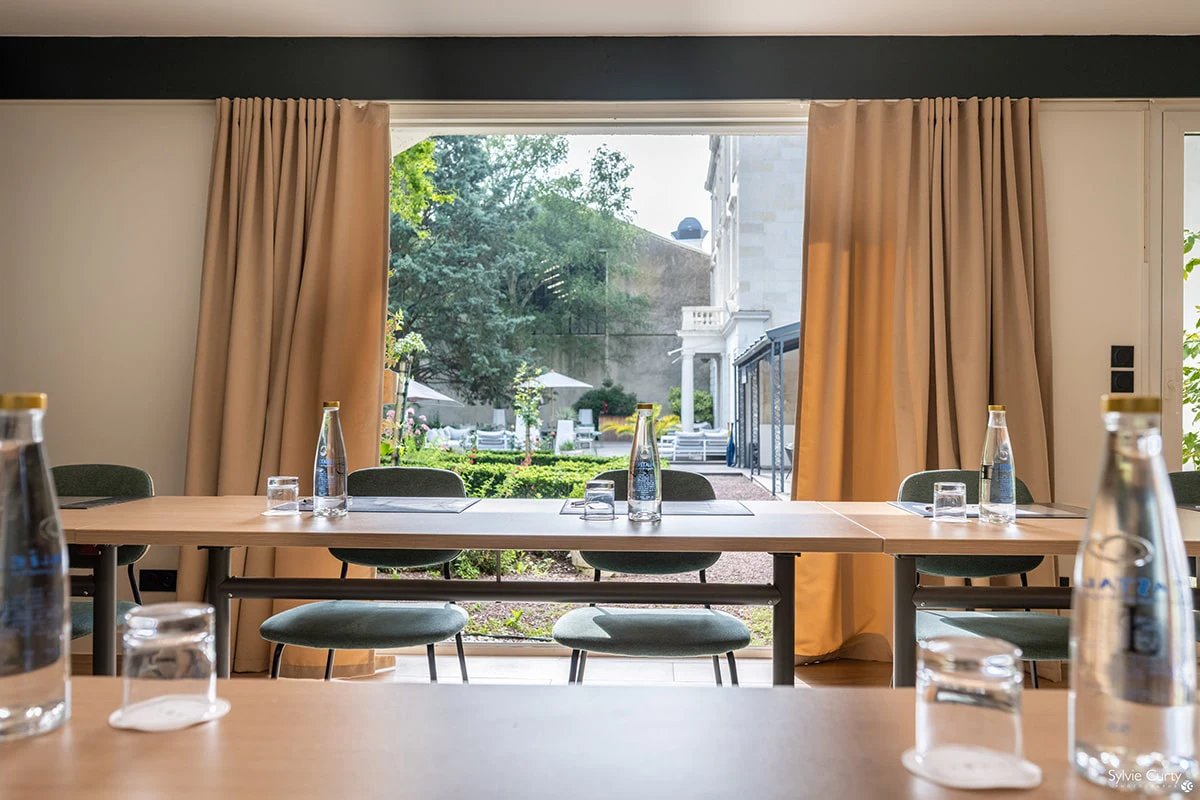 Salle séminaire configuration U Hôtel Champlain La Rochelle avec tables modulables, écran TV et équipement professionnel