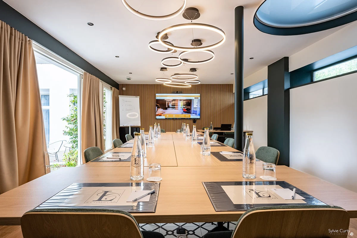 Salle séminaire professionnelle Hôtel Champlain La Rochelle avec table réunion, écran projection et lumière naturelle