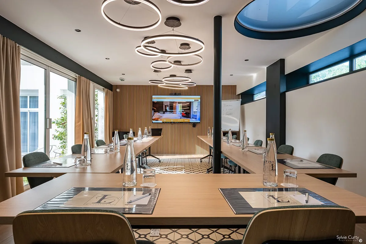 Salle séminaire configuration U Hôtel Champlain La Rochelle avec tables modulables, écran TV et équipement professionnel