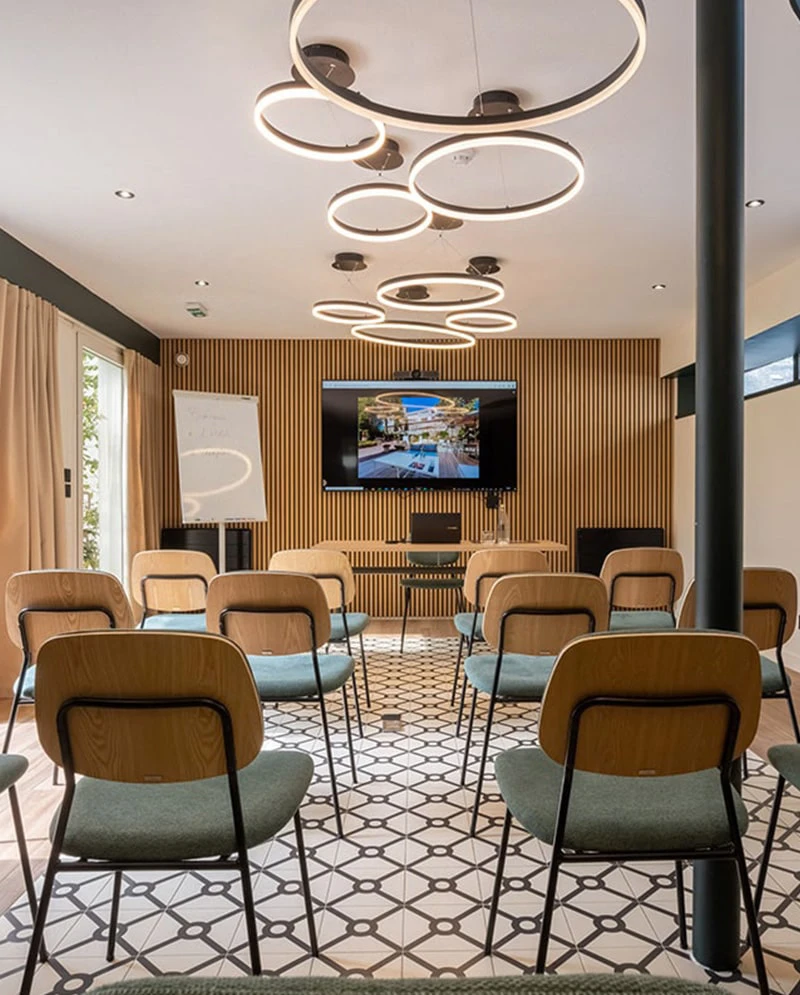 Salle séminaire configuration U Hôtel Champlain La Rochelle avec tables modulables, écran TV et équipement professionnel