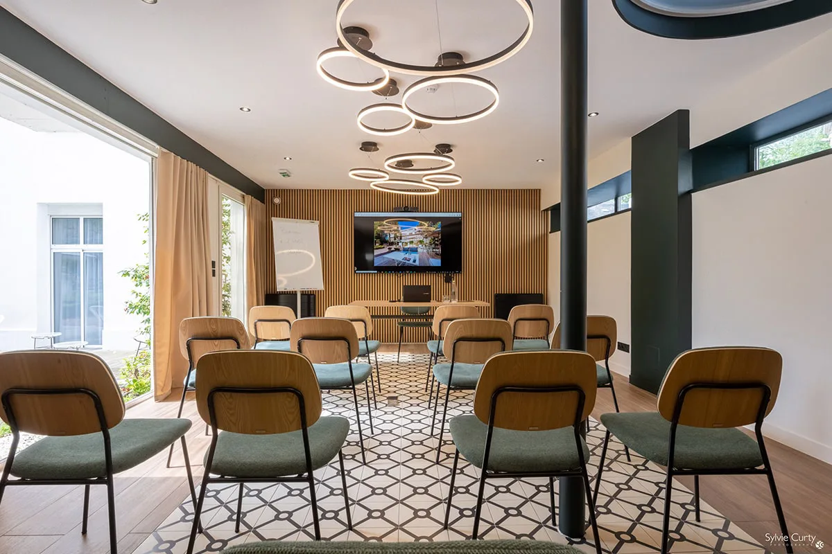 Salle réunion séminaire Hôtel Champlain La Rochelle configuration théâtre avec écran TV, paperboard et lumière naturelle