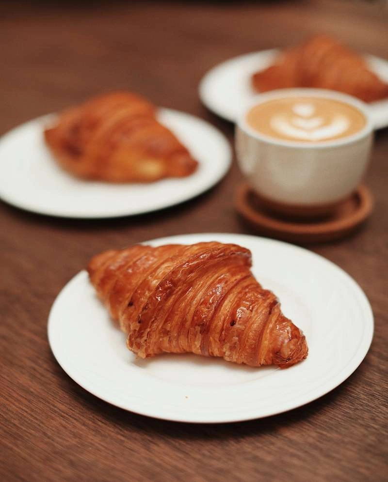 Pause café viennoiseries Hôtel Champlain La Rochelle avec croissants frais dorés et café au lait latte art